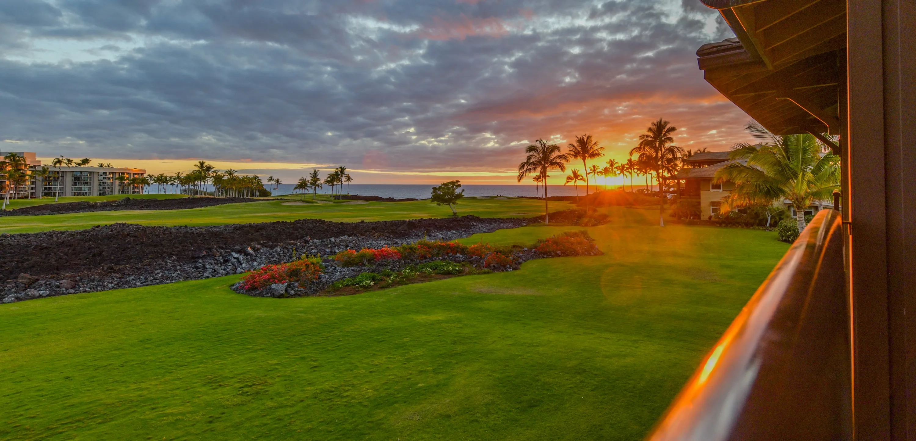 Sunset over the golf course and ocean from the Kai Ho'olili Suite lanai, with lava-rock gardens and palms