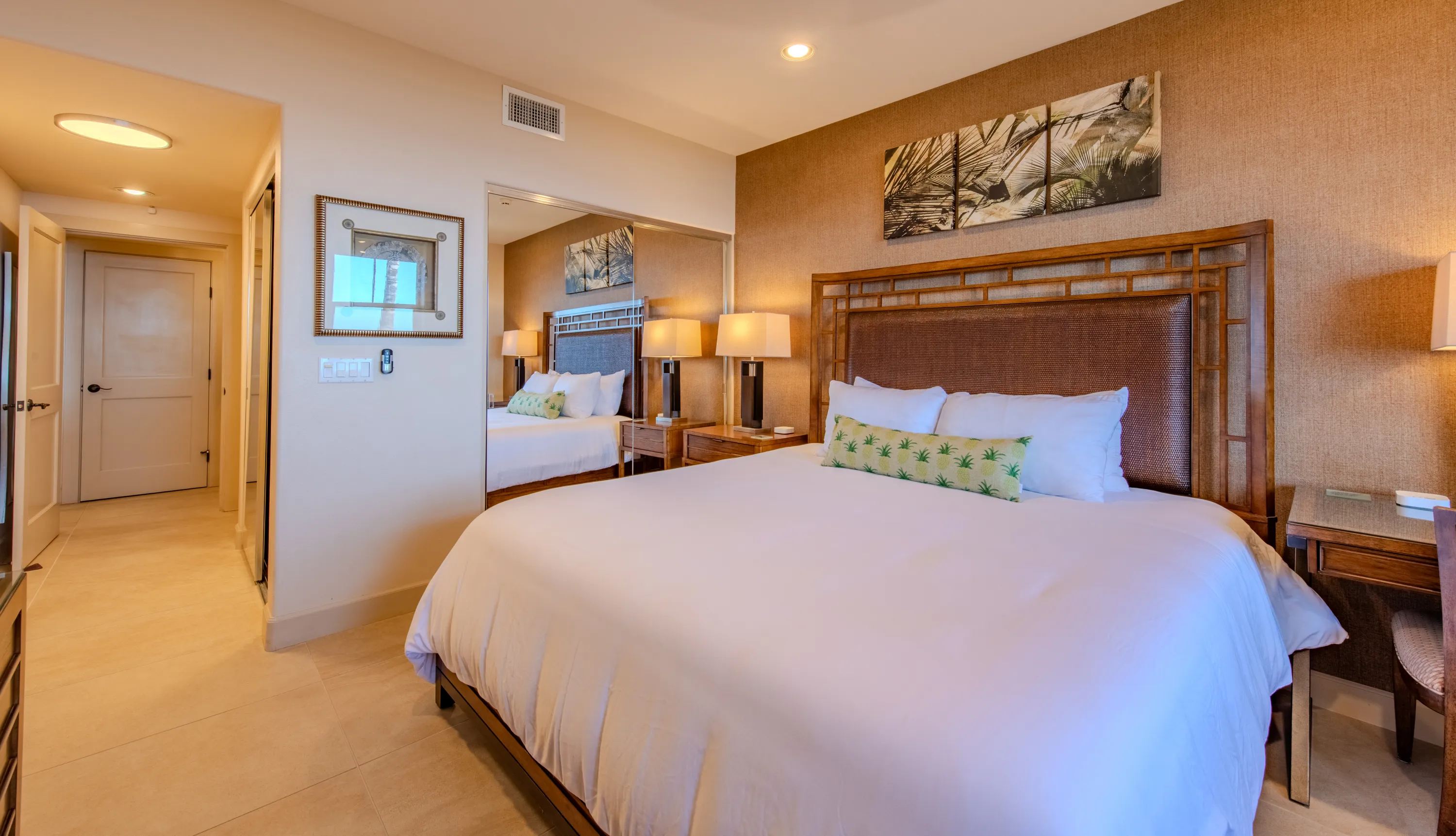 Primary bedroom of the Makai Suite with a king bed, woven headboard, and crisp white linens