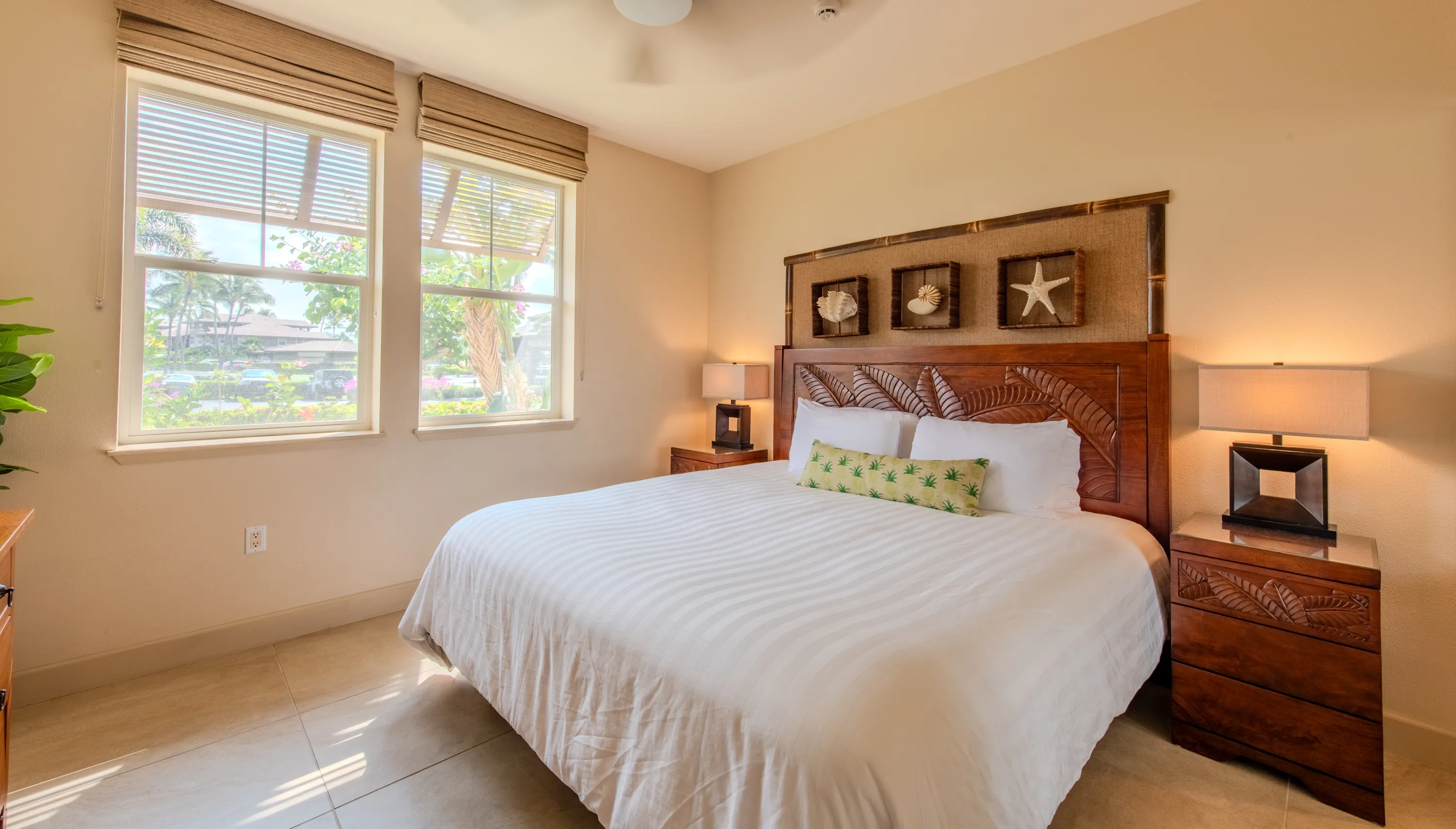 Second bedroom with a king bed, a carved palm-leaf headboard, and a garden view