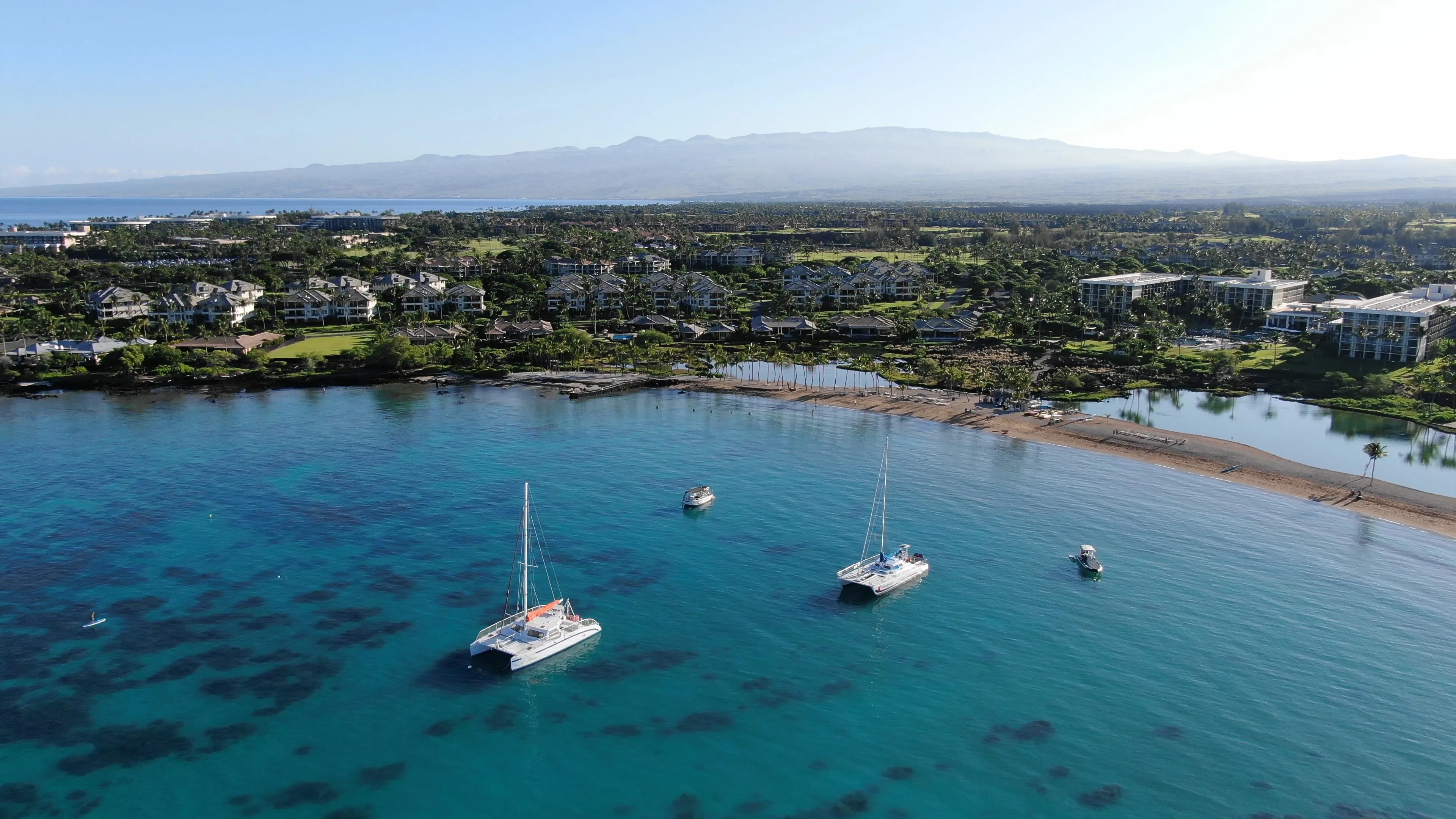 Aerial view of the crescent of 'Anaeho'omalu Bay with its palm-backed sand and calm turquoise water