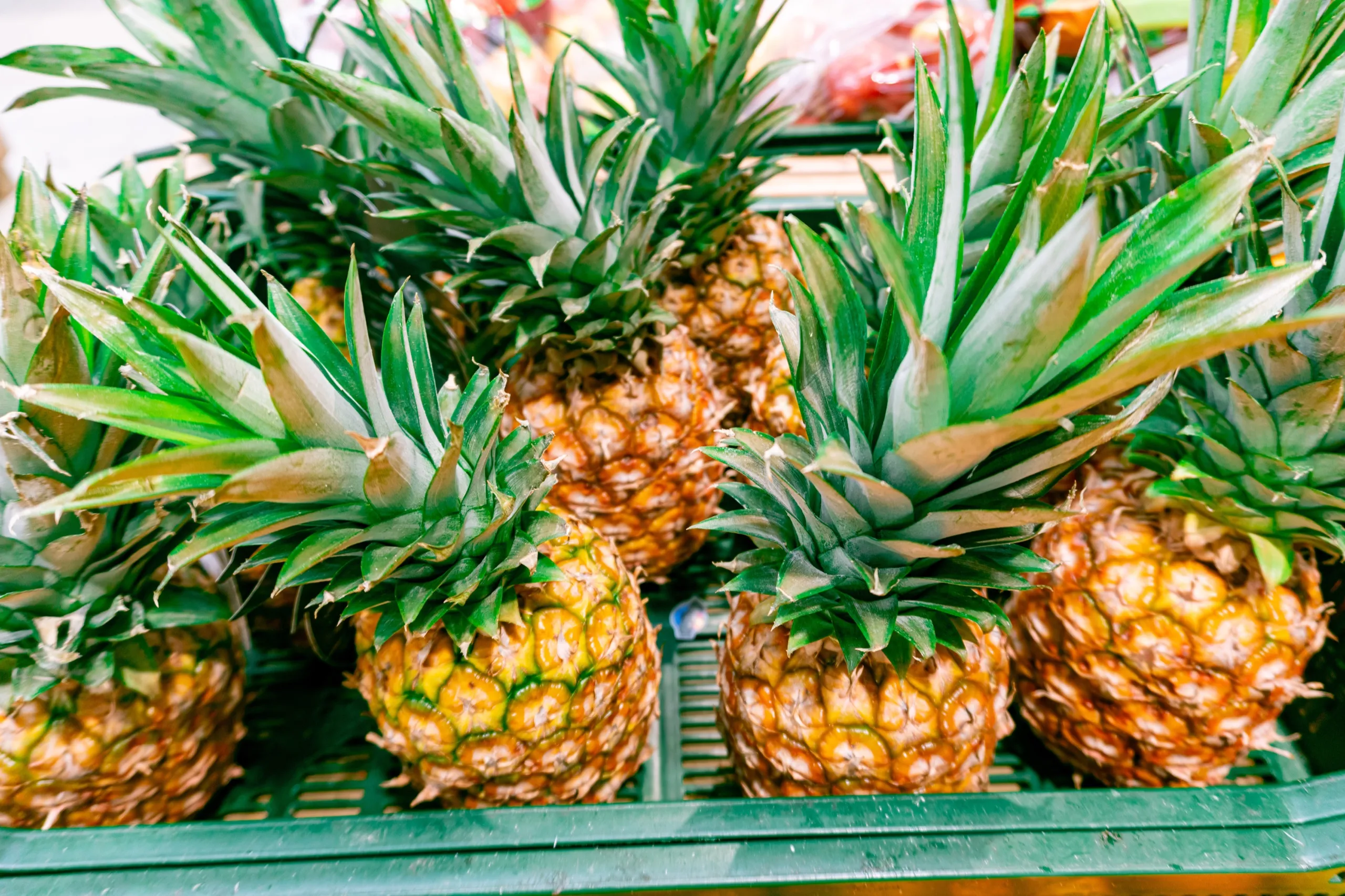 Fresh whole pineapples stacked in a crate at a local market