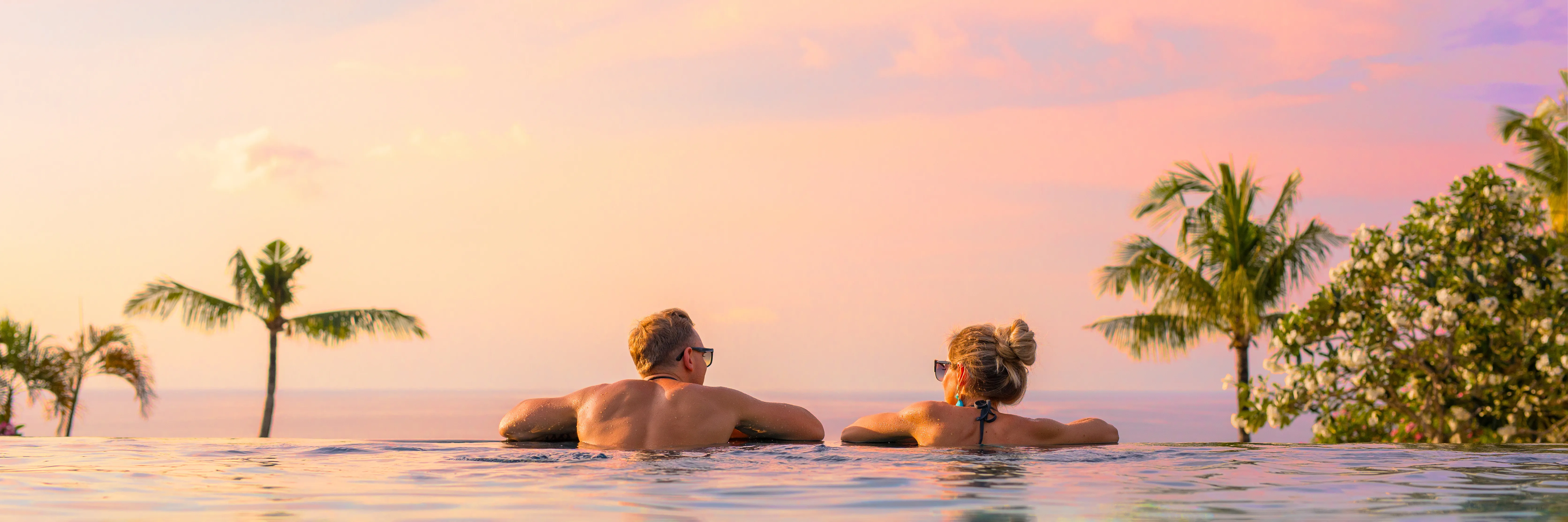 A couple relaxing in an infinity pool at sunset overlooking the Pacific