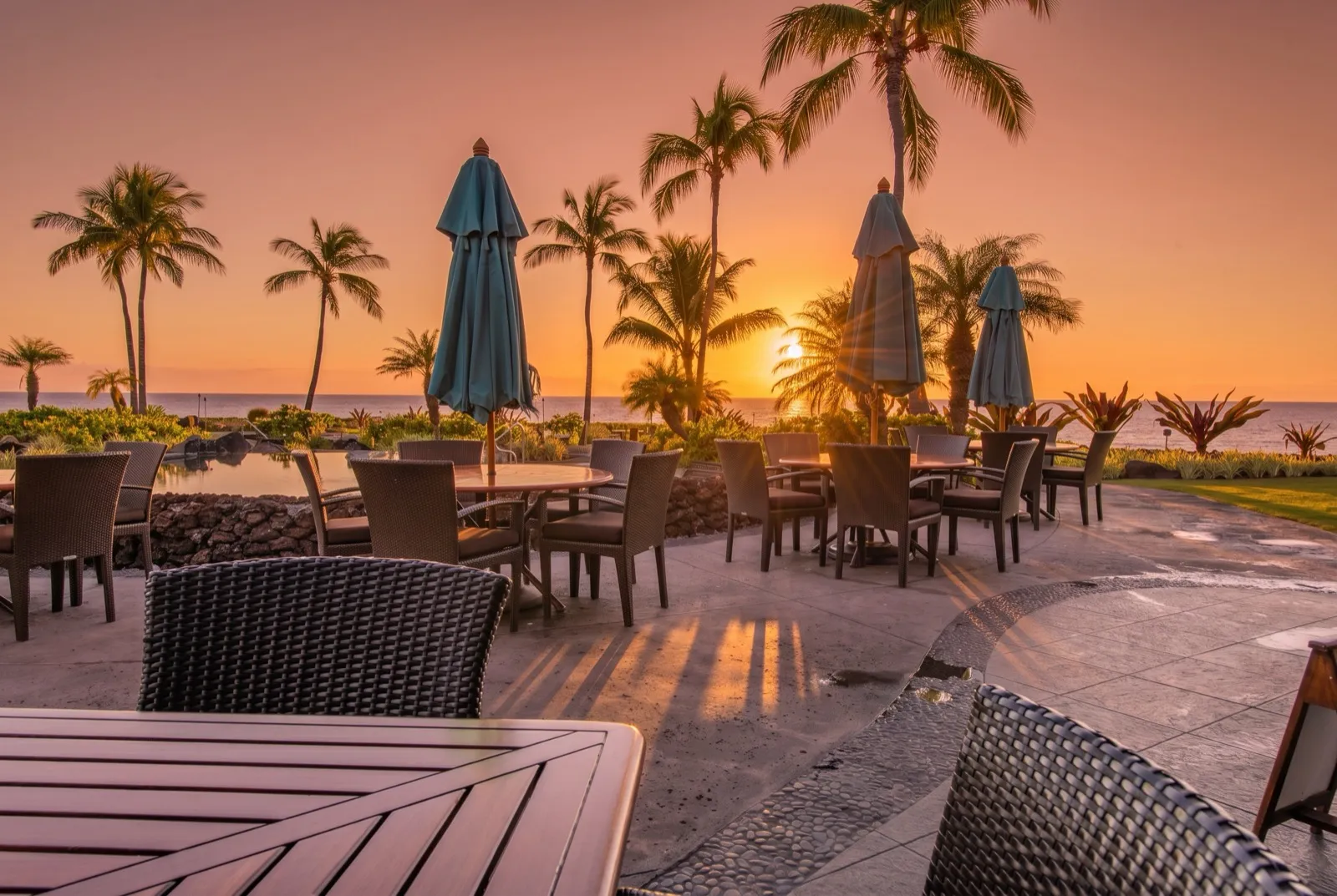 Tables at the Ocean Club restaurant at sunset, looking out over the water at Hali'i Kai