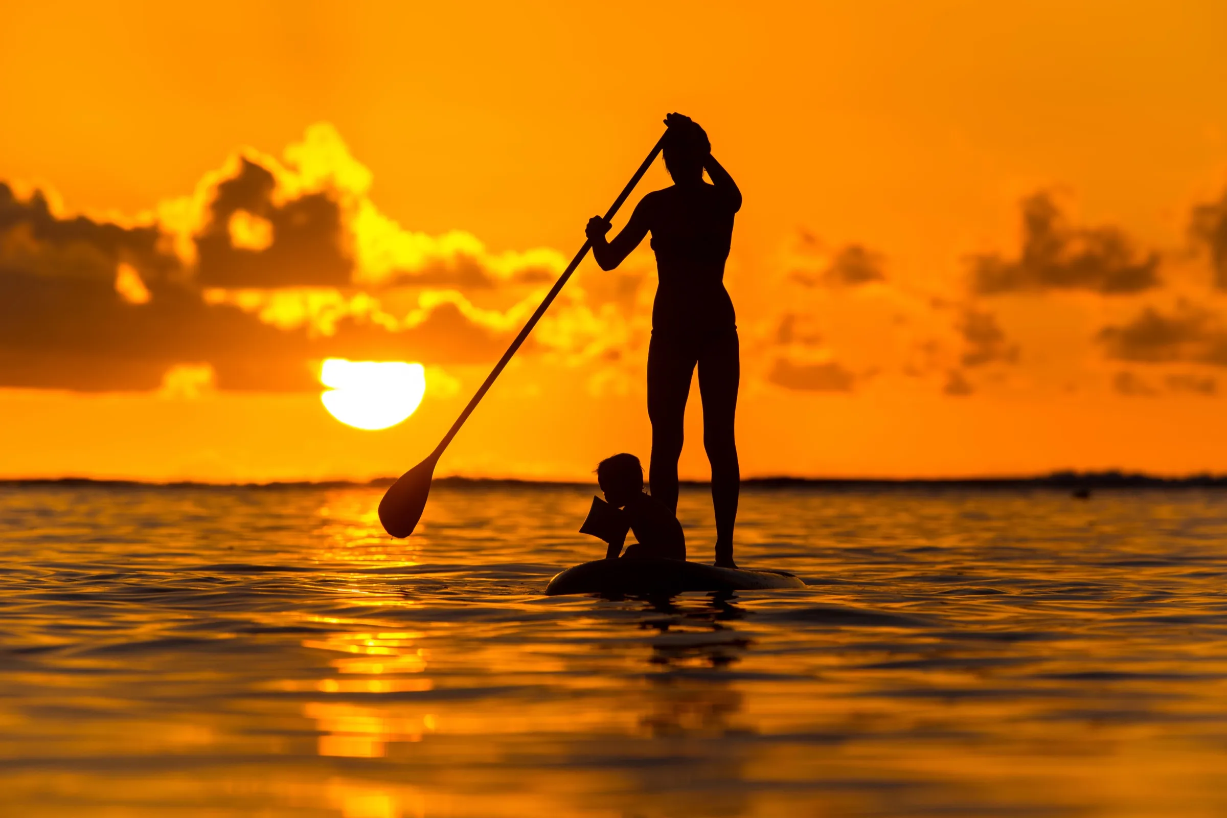 A paddleboarder gliding across calm turquoise water along the Kohala Coast