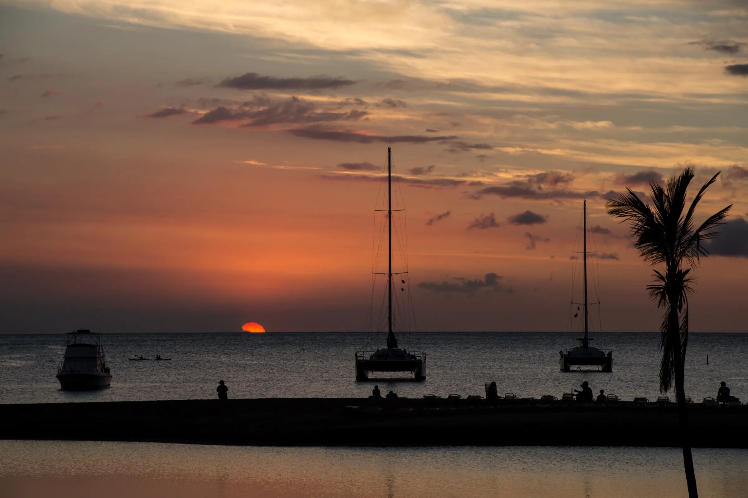 A sailing catamaran on the ocean at sunset off the Kohala Coast